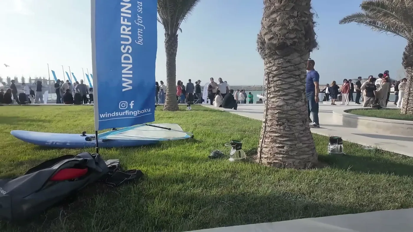Флаги Федерации и Windsurfing Baku, доски с парусами на газоне у причала